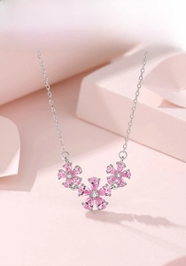 Close-up of pink zircon flower pendant with three delicate blossoms on a silver chain