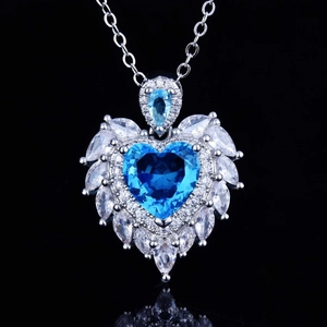 Macro shot of silver angel wing necklace featuring a heart-shaped blue gemstone