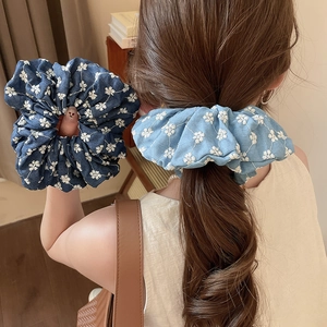 Detail of blue denim scrunchies with white floral embroidery for elegant hairstyles