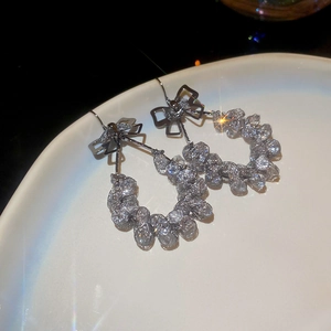 Makroaufnahme von silbernen Schleifenohrringen mit Metallgewebe und Glanzeffekten