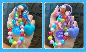 Dettaglio di portachiavi a cuore con perline colorate e ciondoli For Ever in due colori