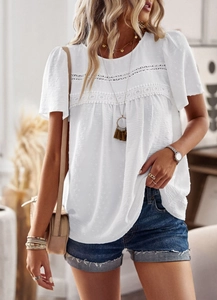 Close-up of white crew neck blouse with bohemian lace patchwork and jacquard details