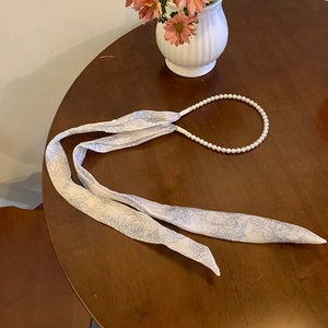 Detail of pearl headband with floral print silk ribbon on a rustic wooden table