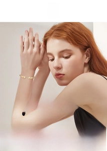 Dettaglio di un bracciale rigido dorato regolabile con sei diamanti tondi brillanti