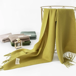 Dettaglio della sciarpa giallo zenzero con nappe, morbida sensazione cashmere ed etichetta