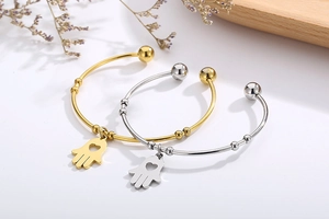 Detail view of gold and silver Hamsa Hand charm bracelets on a white background