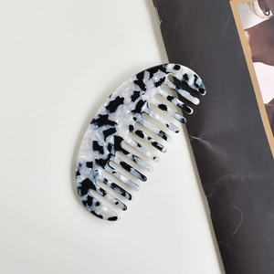 Half-moon acetate hair comb featuring black and white marble tortoiseshell pattern