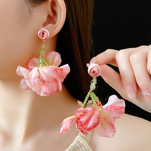 Nahaufnahme der rosa Stoff-Blumenohrringe mit grünen Perlen an einem weiblichen Model