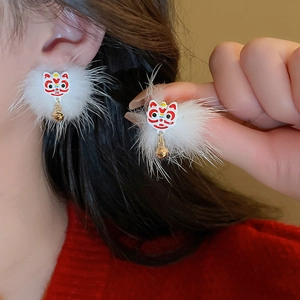 Close-up of fluffy white pom pom earrings with red lion dance motif and golden bells