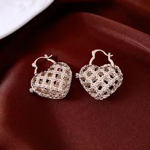 Chic hollow heart rose gold hoop earrings with woven texture on red satin background