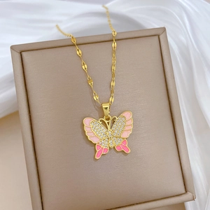 Dettaglio macro del ciondolo a farfalla dorata con smalto rosa e strass lucidi