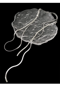 Silver snake bone chain necklace displayed on a textured glass plate with dark background