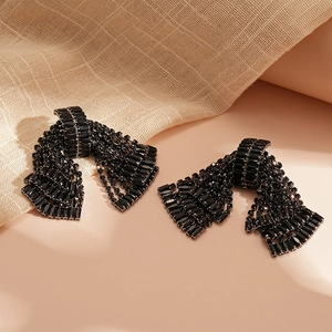 Macro shot of tiered black rhinestone tassel earrings with a 3D bow and silver posts