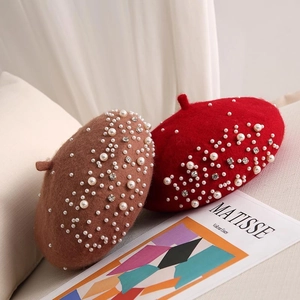 Detail of wool beret hats with luxury pearl and rhinestone embellishments in red and brown