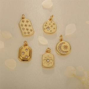 Golden star and moon pendants with white zircon stones on a minimalist cream background