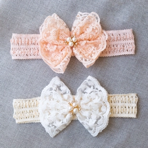Lace baby headband set with pearl bows in pink and beige on grey fabric