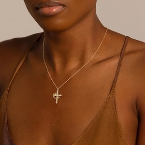 Close-up of a model wearing a gold 18K crown cross pendant necklace with zircon stones