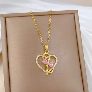 Luxurious gold heart pendant necklace with pink gemstones and crystals on beige box