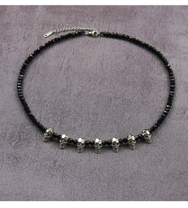 Detail of Gothic beaded necklace featuring seven silver skull pendants and faceted black beads