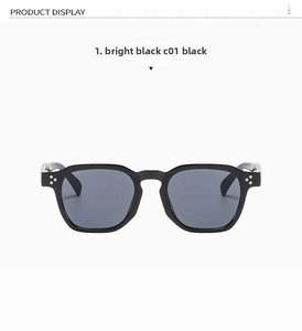 Detail of bright black square sunglasses with three round silver rivets on the frame corners