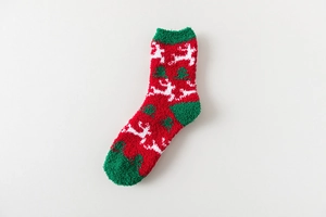 Detail of soft coral fleece Christmas socks featuring white reindeer and tree patterns