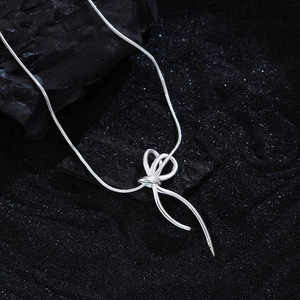 Silver bow knot pendant necklace with sleek snake chain shown on a textured black background