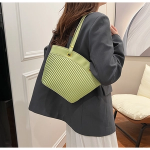 Detail of light green pleated tote bag featuring golden metal ring and shoulder strap
