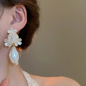 Gros plan de boucles d'oreilles fleurs blanches avec grandes perles sur modèle