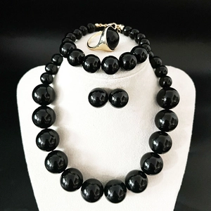 Detail of elegant black pearl jewelry set including necklace, bracelet, and gold ring