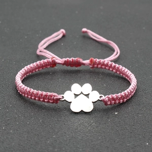 Macro detail of hand-woven pink luck cord bracelet featuring silver dog paw charm