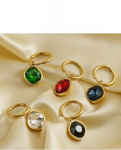 Detailed view of geometric 18K gold-plated earrings with colorful zircon drops on silk