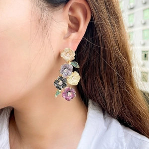 Macro shot of long floral drop earrings with multicolored zircons on a model
