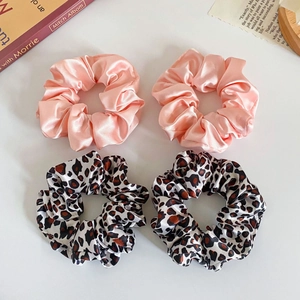 Detail of 4-piece set floral and leopard print satin hair scrunchies on a white surface