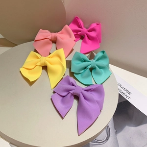 Detail of vibrant neon fabric bow hair clips in five colors on a minimalist display