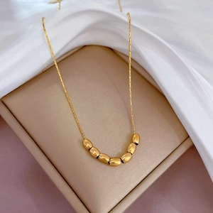 Close-up of golden bean-shaped beads on a delicate chain in a velvet jewelry gift box