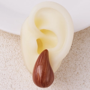 Macro shot of brown teardrop-shaped drop earring with wood grain resin on model ear