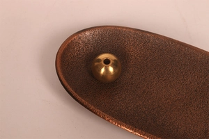 Close-up of bronze textured incense burner tray with spherical brass holder for meditation