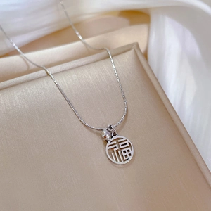 Détail du collier en acier titane argenté avec pendentif Fu sur une boîte d'exposition