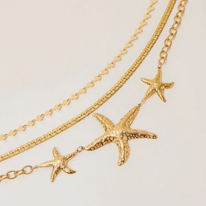 Detail of layered gold starfish necklace featuring sleek snake chain and textured pendants