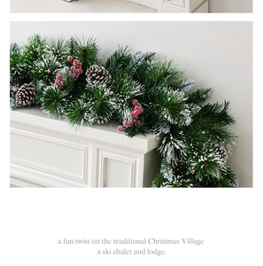 Lush snow-flocked Christmas garland with red berries and pinecones on a white fireplace