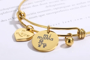 Close-up of adjustable gold steel bracelet with Love heart and Mi Mama pendants