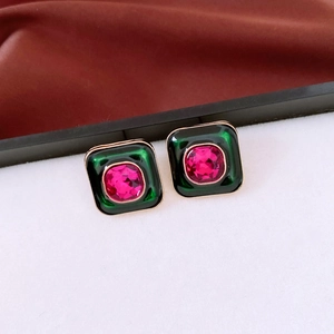 Detail of vintage square earrings with green enamel and pink gemstone in gold setting