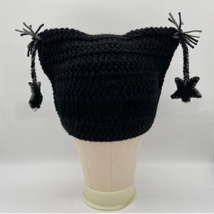 Close-up of black crochet knit cat ear beanie with star charm and fringe details
