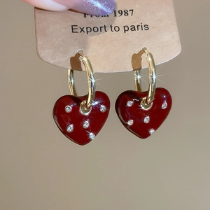 Macro shot of red heart drop earrings with shimmering crystals on gold hoops