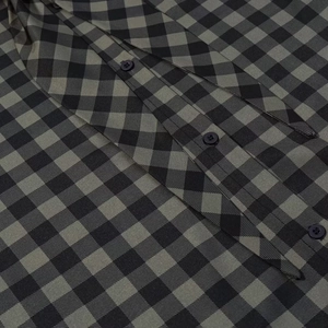 Detailed view of dark green plaid shirt with black buttons and woven texture finish