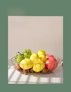 Close-up of a gold metal fruit basket with an oval openwork design and fresh fruits