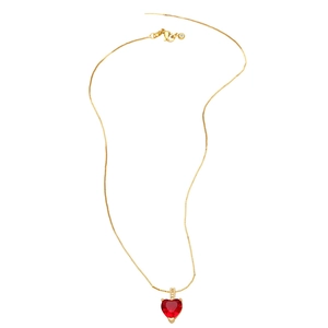 Détail du collier doré avec pendentif cœur rouge et petits cristaux blancs