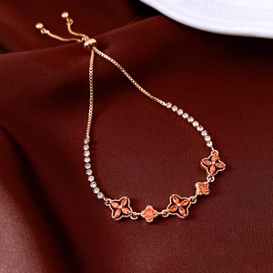 Detail of adjustable 18K gold plated flower bracelet with orange gems on red velvet