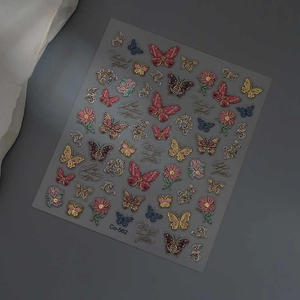 Détail de stickers à ongles papillon 3D avec dorure, motifs floraux et finitions métalliques