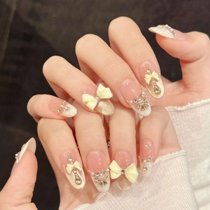 Pink nude press-on nails with 3D bows, pearls, and crystals in long almond shape